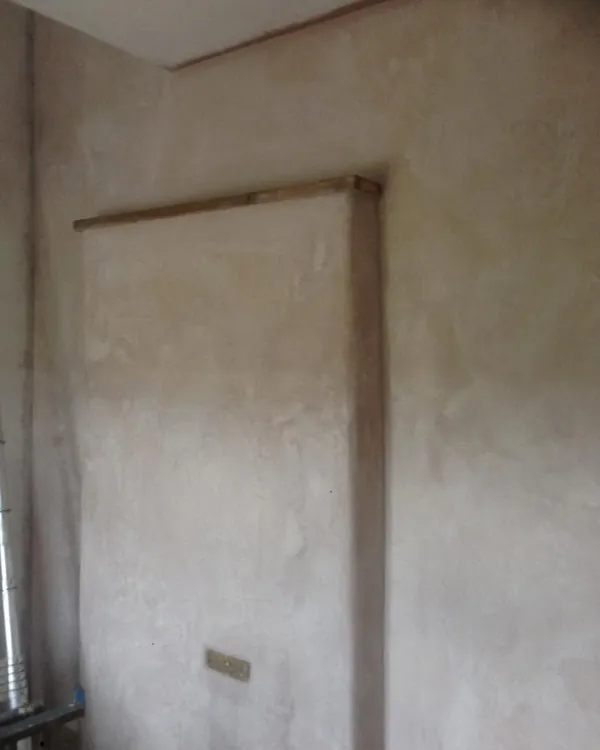 Freshly plastered chimney breast with an exposed timber lintel across the top