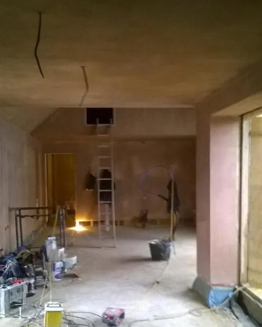 Long room with freshly plastered walls and ceiling, a ladder up to a loft hatch and a deep plastered window reveal