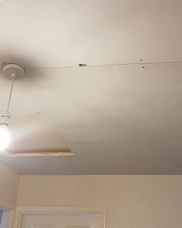 Plasterboard sheets fixed across a bedroom ceiling around the light fitting, before skimming