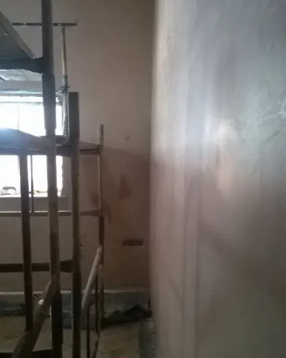Tall freshly plastered wall with a mobile scaffold tower standing beside it