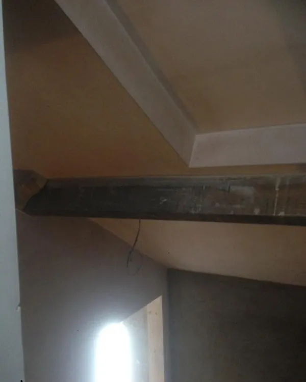 Plastered sloping ceiling with a boxed section above a dark exposed beam